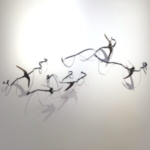 a wall installation of 5 paper swifts attached to curling ribbons of dark blue paper